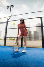 Model wearing mocha Soi Sculpt Short on blue tennis court